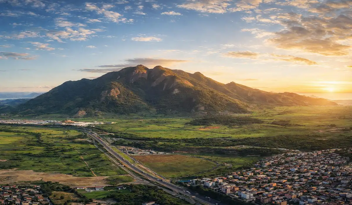 Vista imponente do Mestre Álvaro na Serra, ES, com vegetação de Mata Atlântica e a cidade ao fundo.