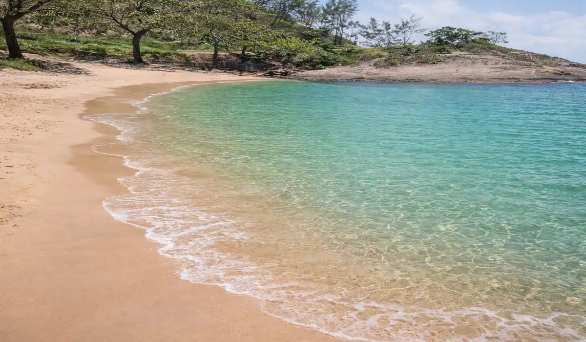Paisagem da Praia Secreta em Vila Velha com águas cristalinas azul-turquesa e areia dourada aos pés do Morro do Moreno.
