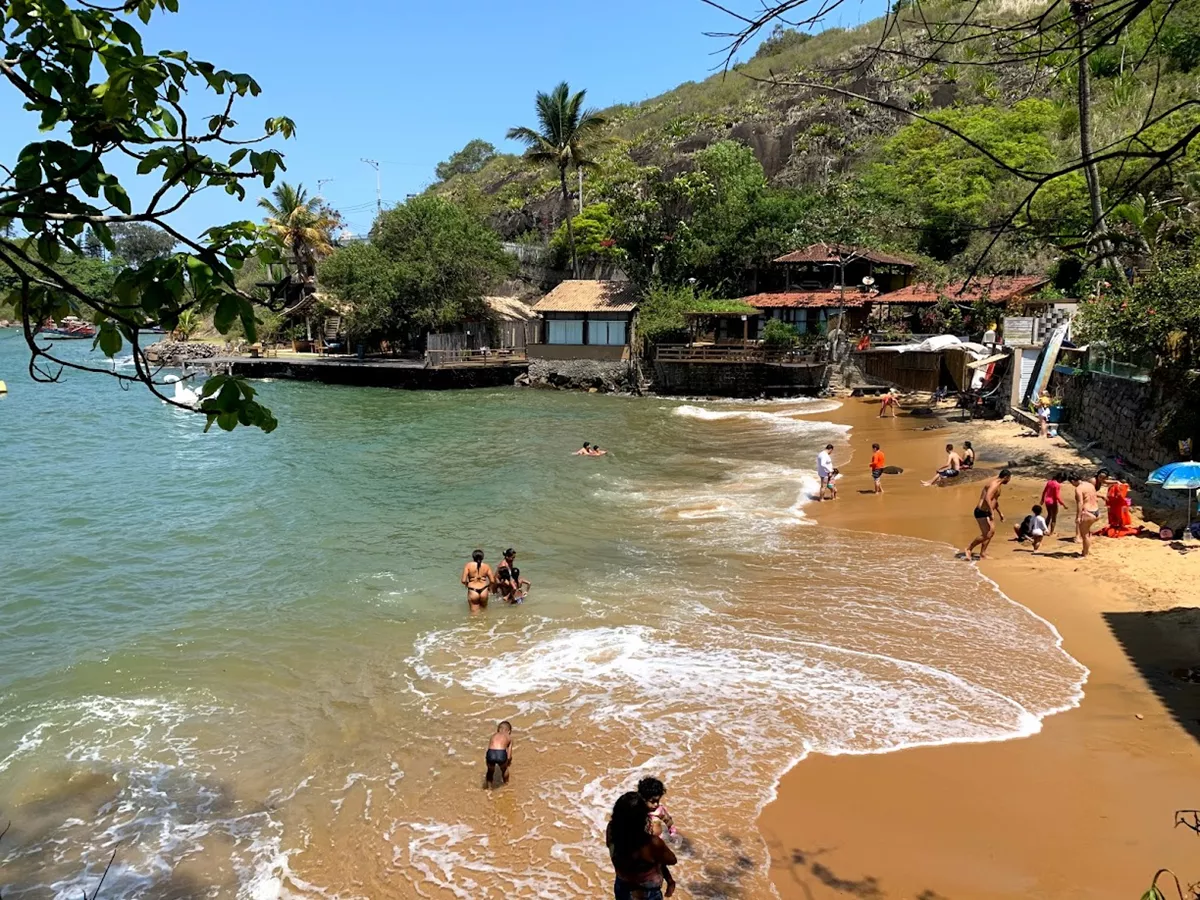 Barcos de pesca ancorados na Praia do Bananal em Vila Velha, com águas calmas e a Terceira Ponte ao fundo.