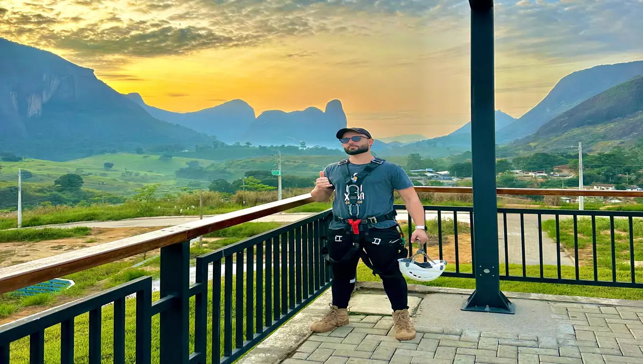 Aventureiro descendo na Tirolesa de Pancas, a maior da América Latina, com os Pontões Capixabas ao fundo.