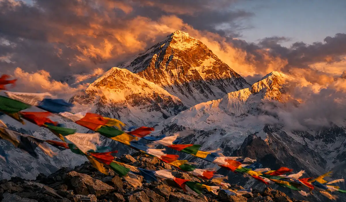 Pico do Monte Everest com nuvens dramáticas e bandeiras de oração, ilustrando o ambiente hostil da Zona da Morte.