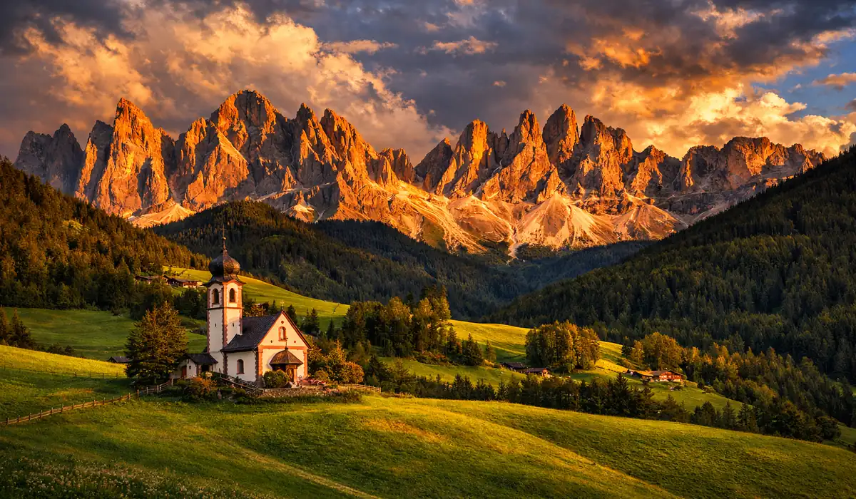 Igreja de Santa Maddalena em Val di Funes com as montanhas Odle ao fundo durante o pôr do sol.